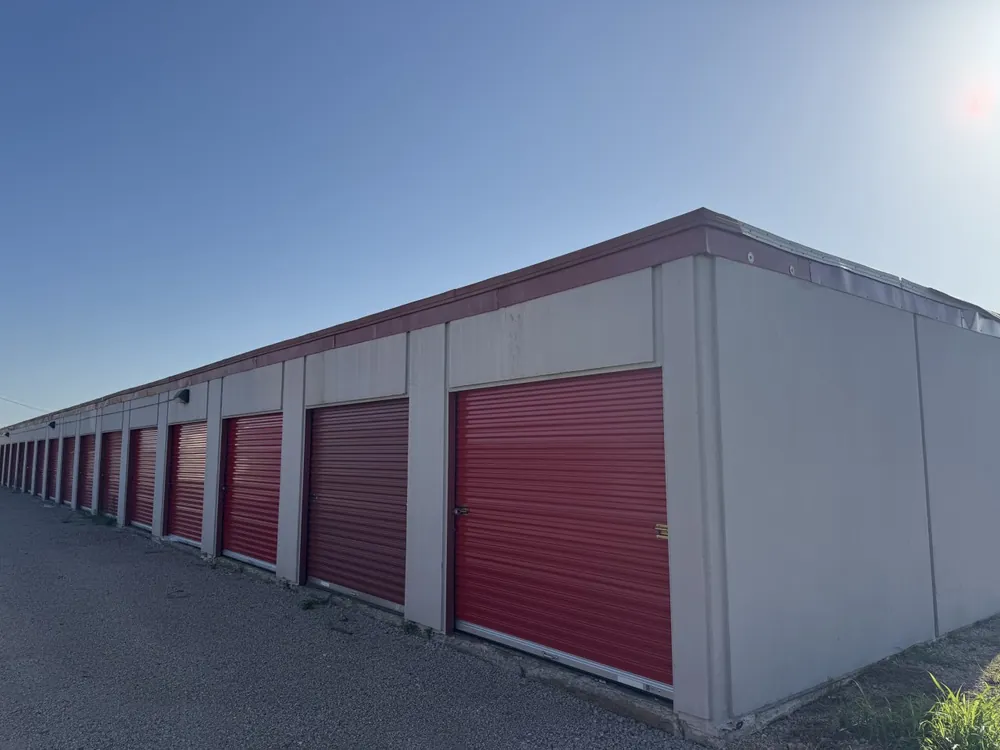Corner of a storage building with red doors under a clear blue sky
